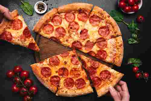 Picking slice of pepperoni pizza. Hands picking pizza slice. Top view of tasty hot pepperoni pizza on black concrete background